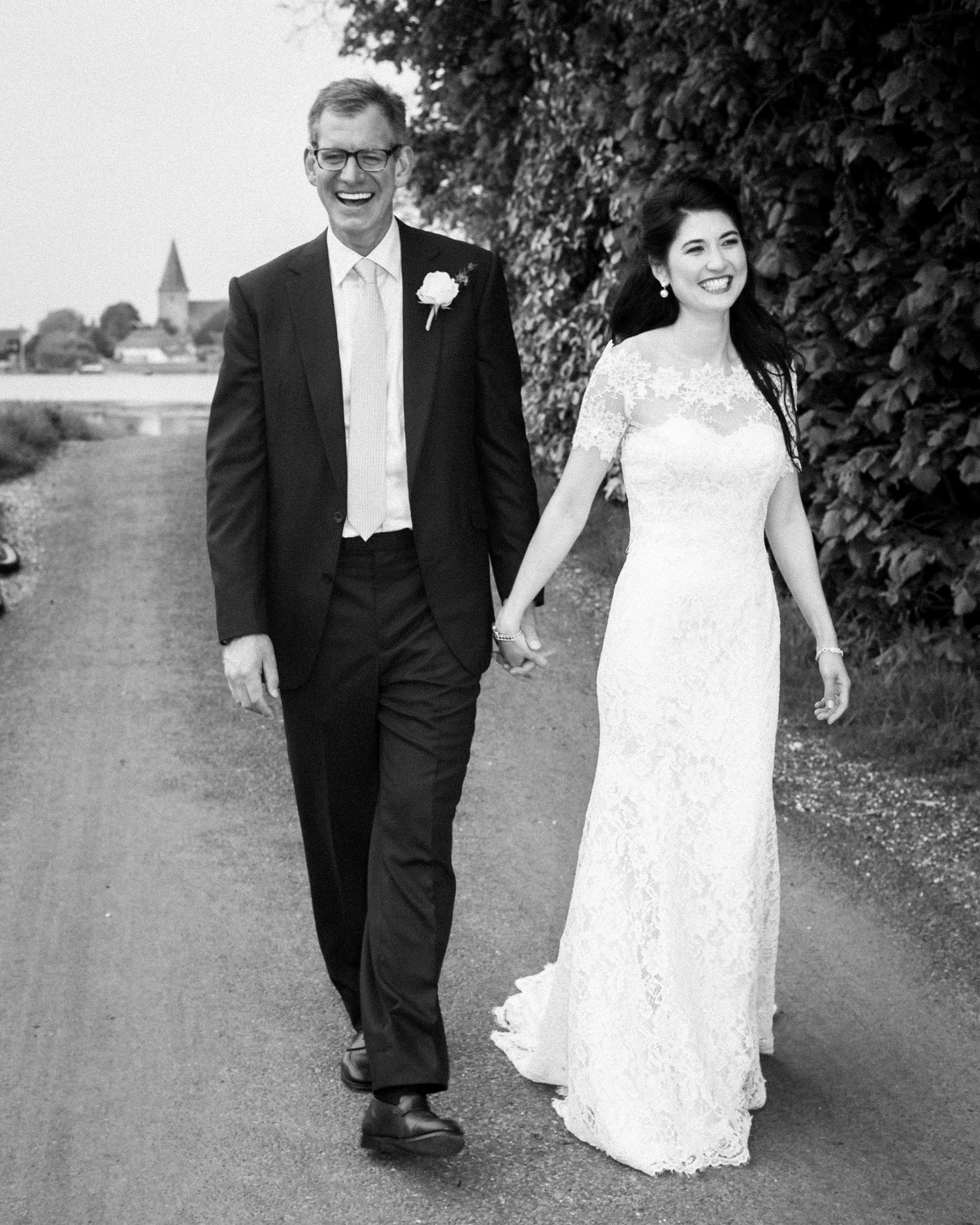 A newly wed couple takes a romantic stroll along a Bosham path in formal wedding attire.