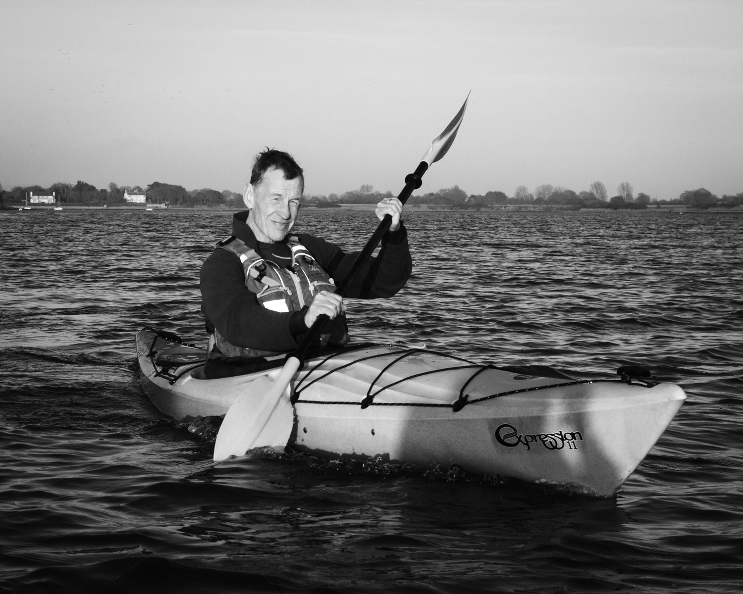 Black and white photo of kayaker holding paddle on open water Chichester Harbour