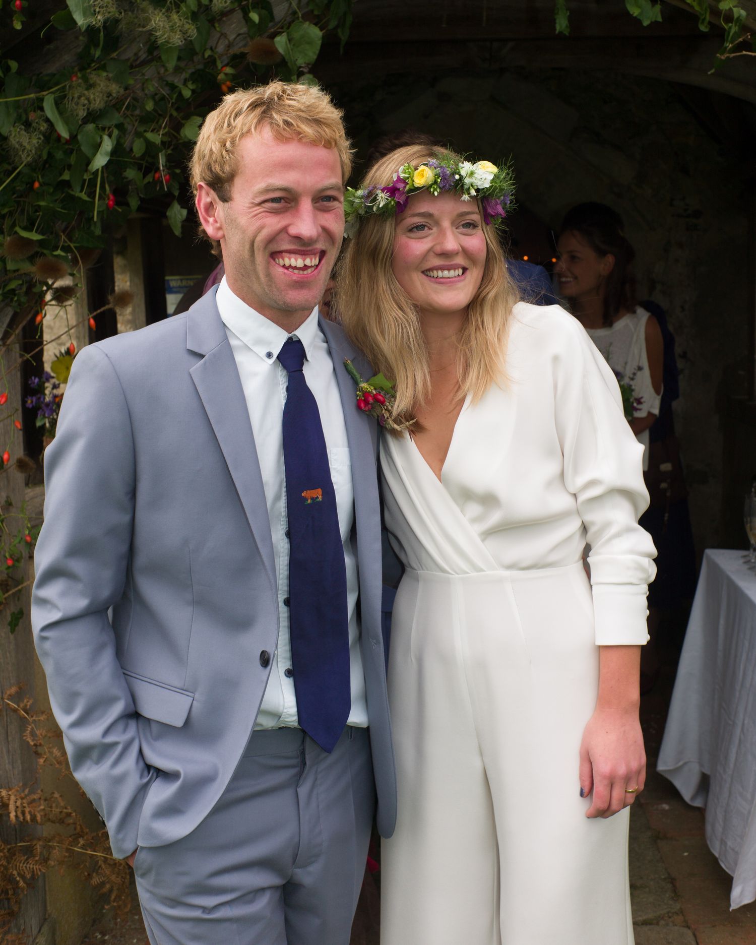 Wedding couple poses outdoors in grey suit and white dress during their celebration.