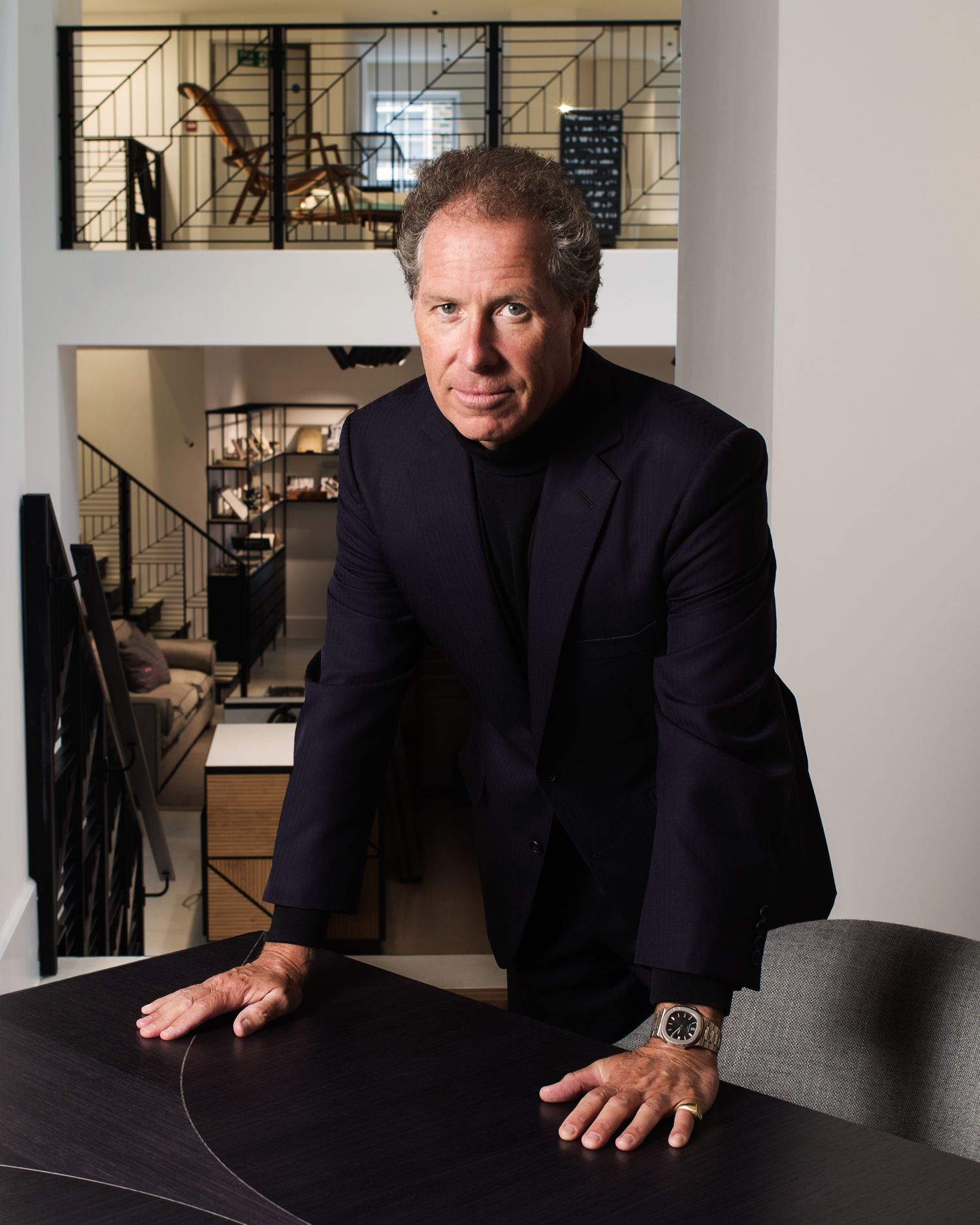Professional portrait series in a modern office setting with dark furniture and stairs.