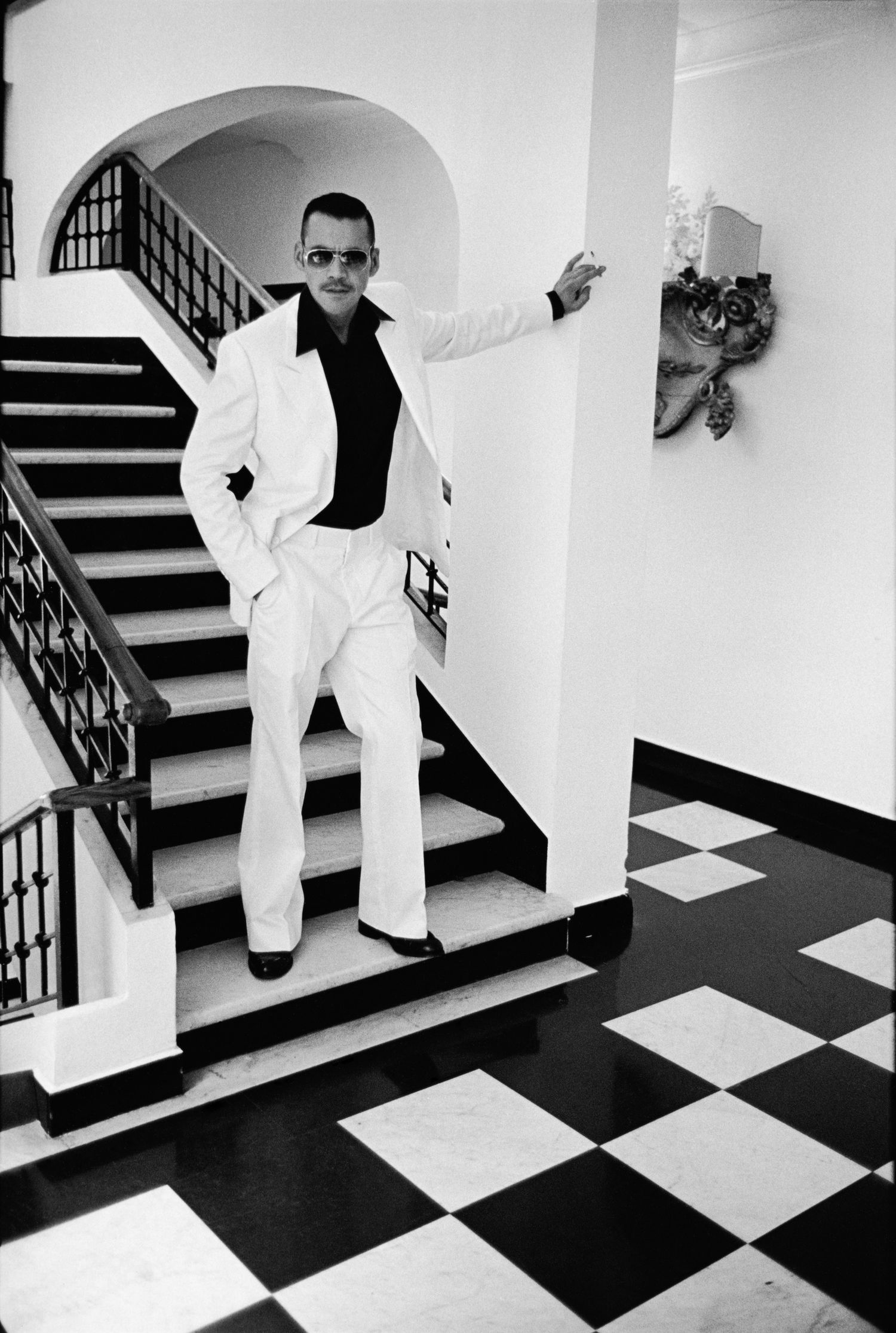 Series of black and white photos showing figure in white suit on checkered floor with stairs.