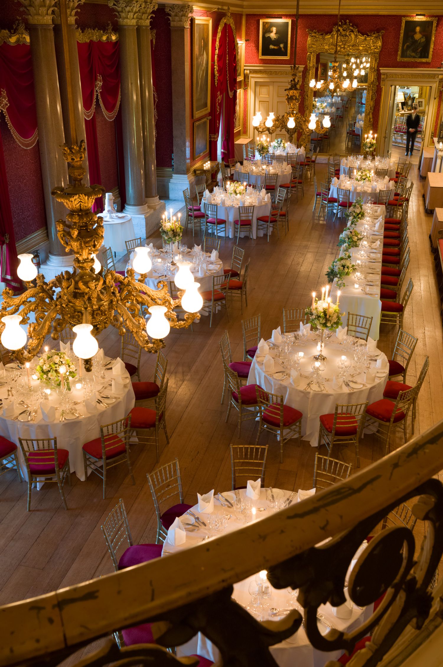 Luxurious ballroom set for wedding reception with crystal chandeliers and round tables with white linens.