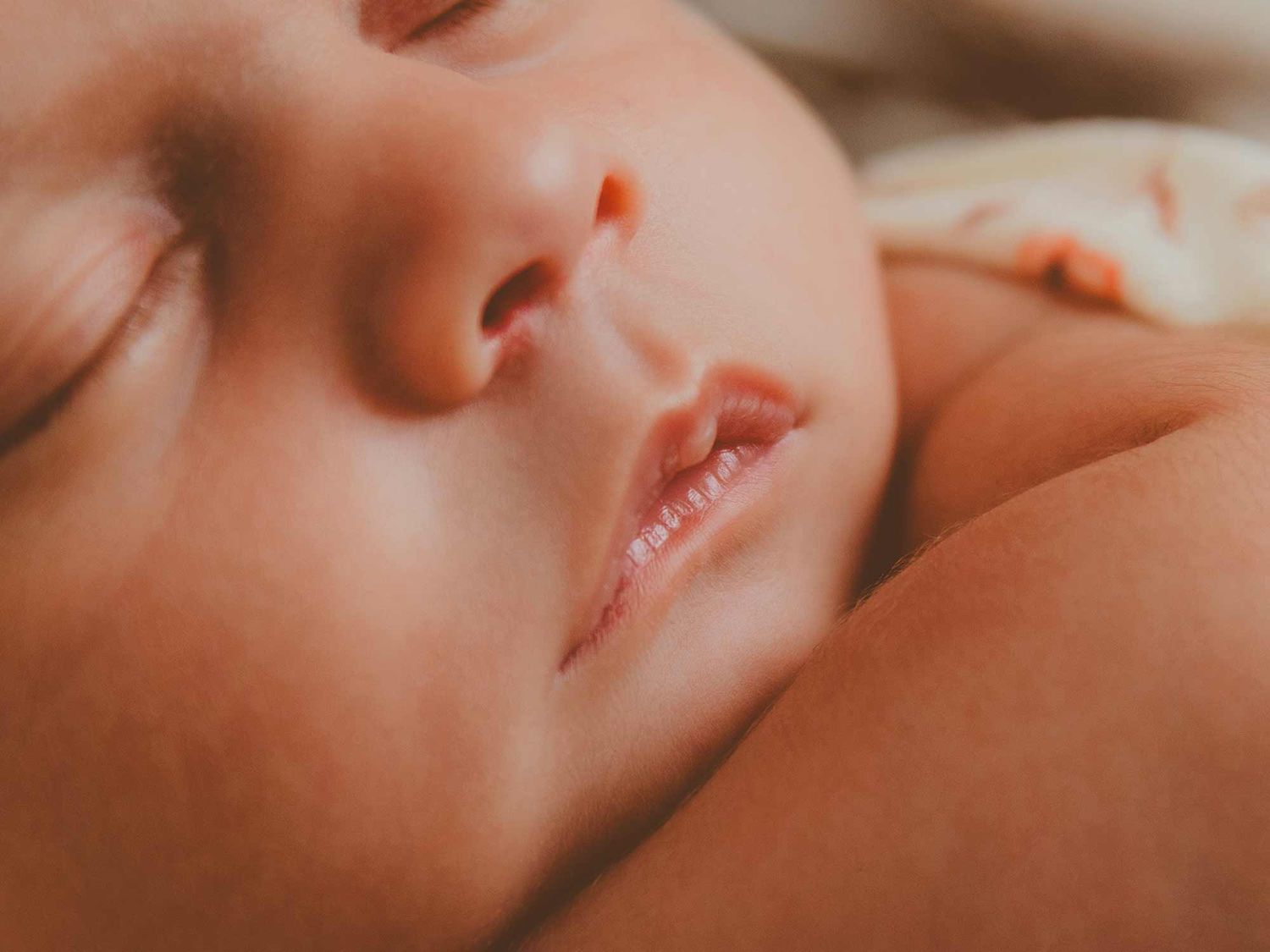 Primer plano del rostro de un bebé recién nacido dormido, con rasgos delicados y piel suave.