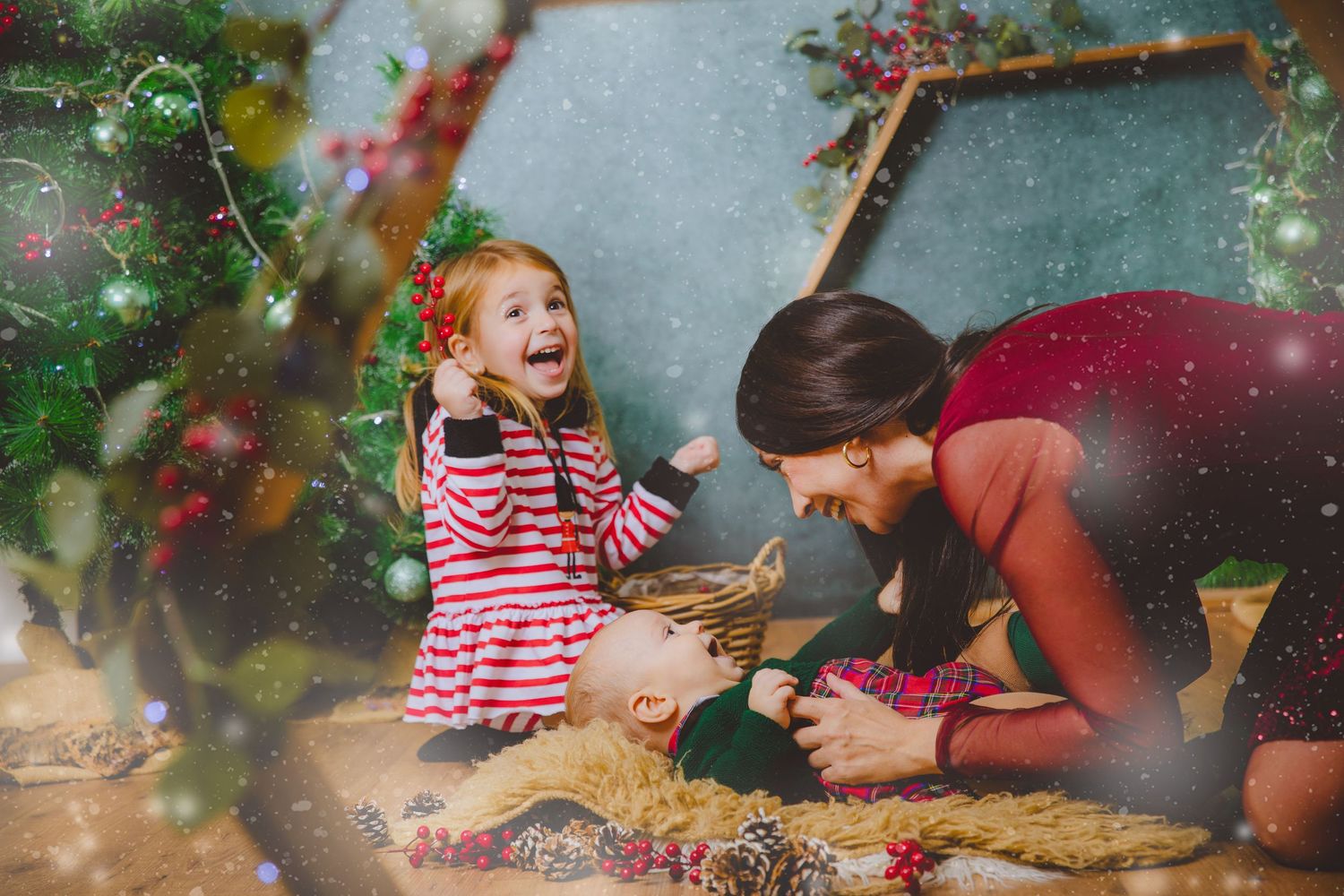 Niño pequeño riendo con pijama de rayas comparte un momento alegre con su madre en un ambiente navideño festivo.