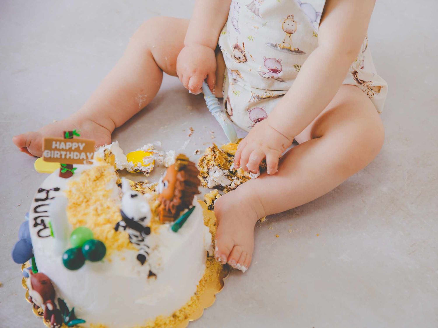 Bebé rompiendo su tarta de cumpleaños con las manos durante la sesión de fotos de smash cake