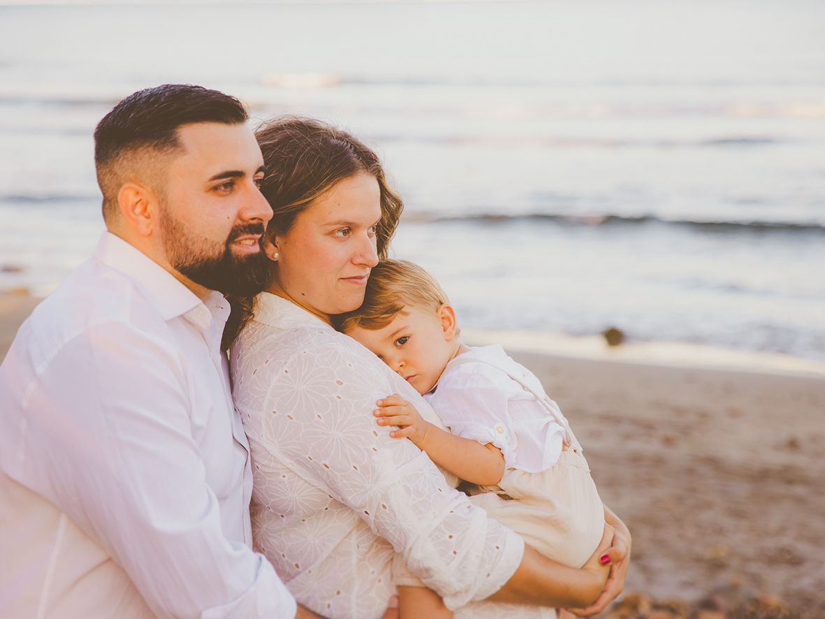 Familia abrazada a orilla del mar durante su reportaje de maternidad en Almería.
