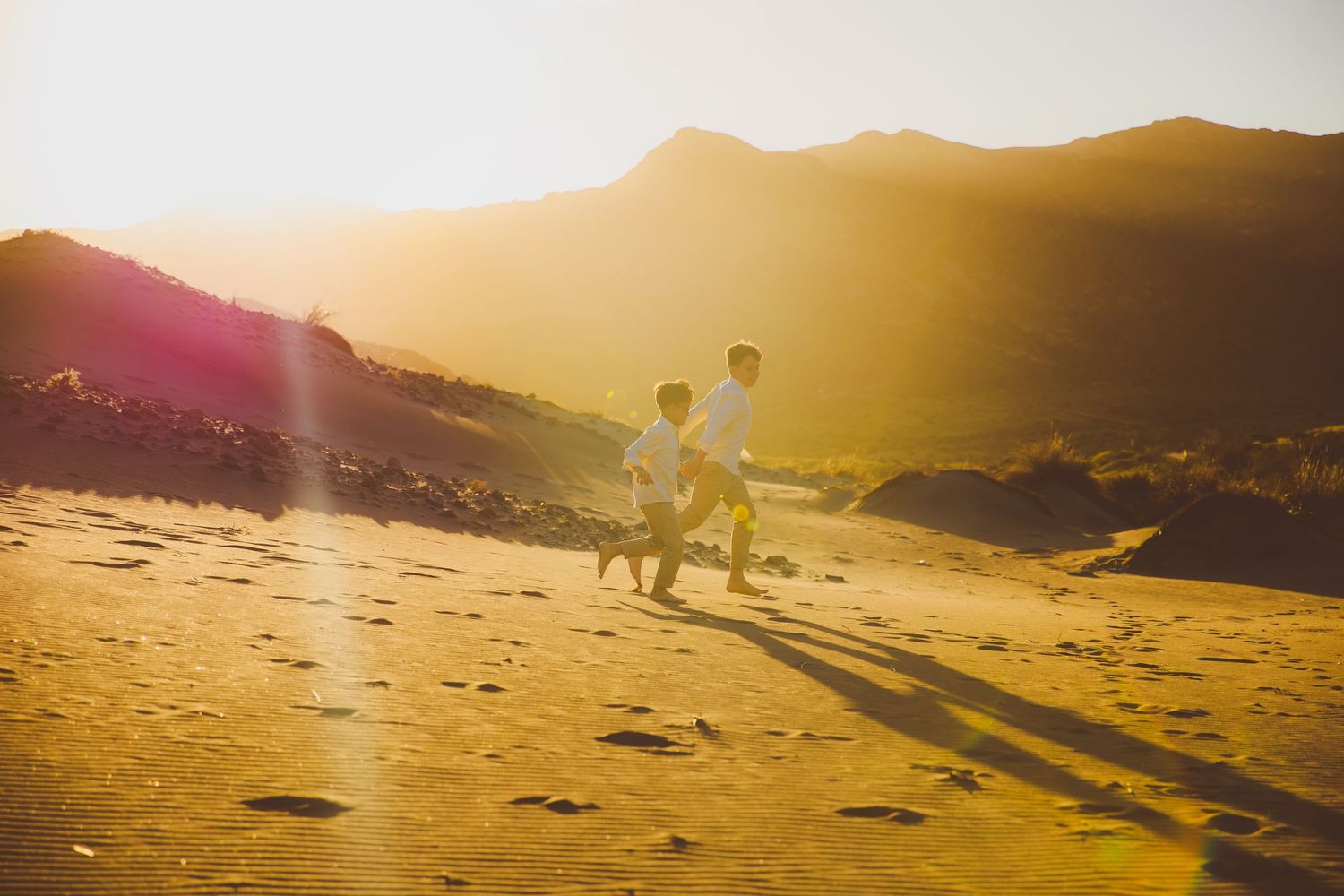 Niños corriendo por las dunas de las playas de Cabo de Gata con una luz dorada de atardecer en su sesión de exteriores.