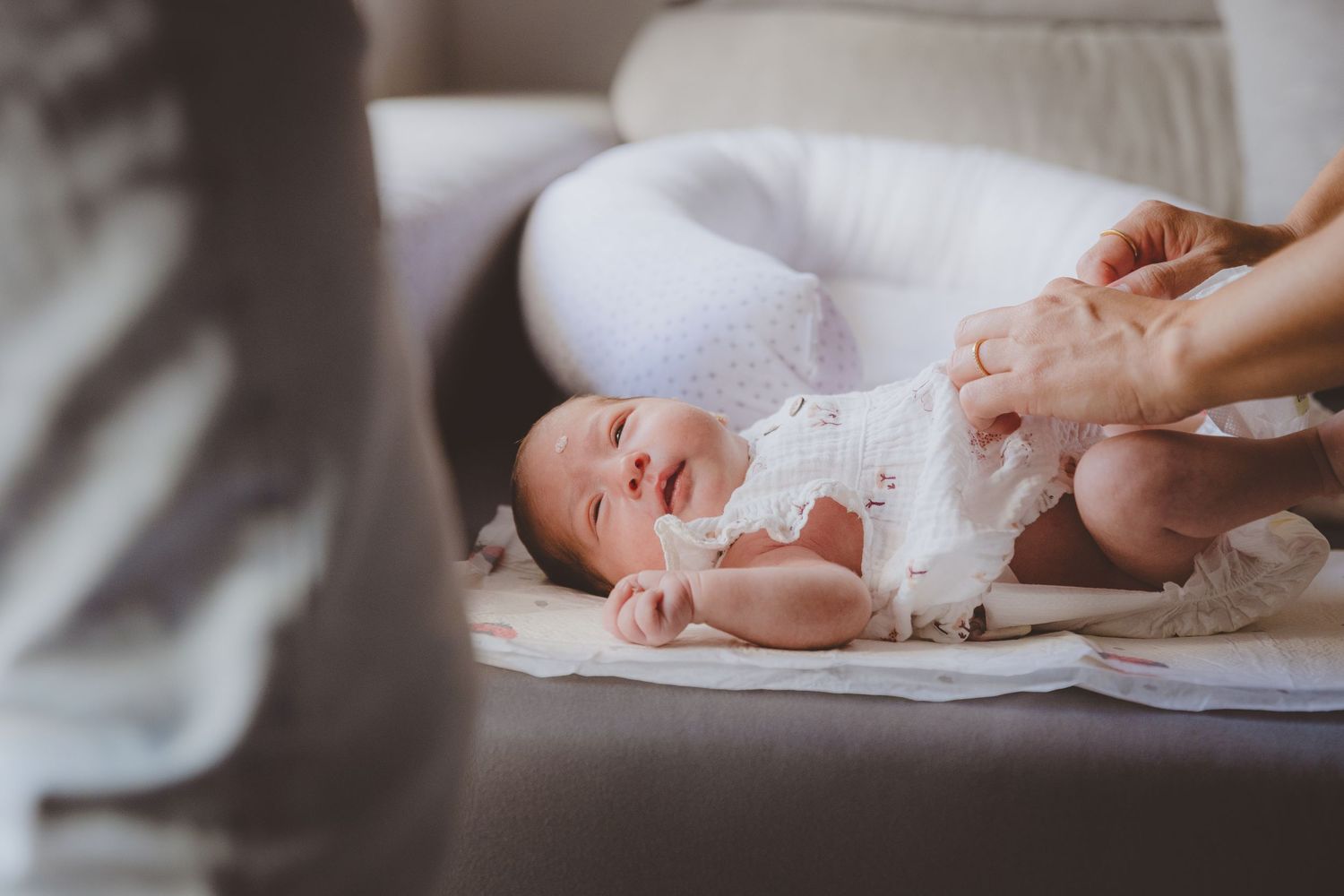 Bebé fotografiado en Almería, mientras su mamá le cambia la ropita durante su sesión de recién nacida en casa.