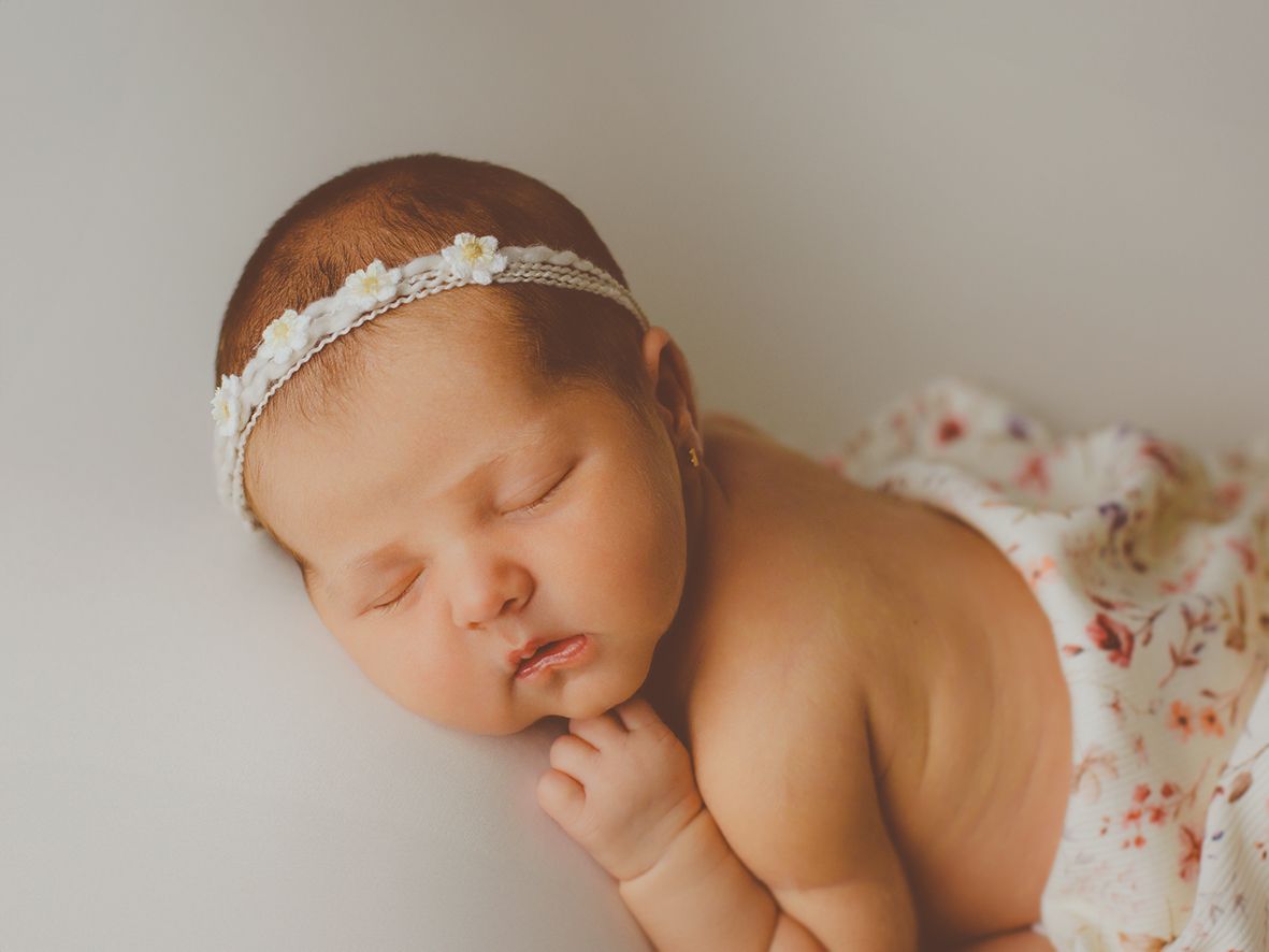 Recién nacida dormida plácidamente con una diadema de margaritas.