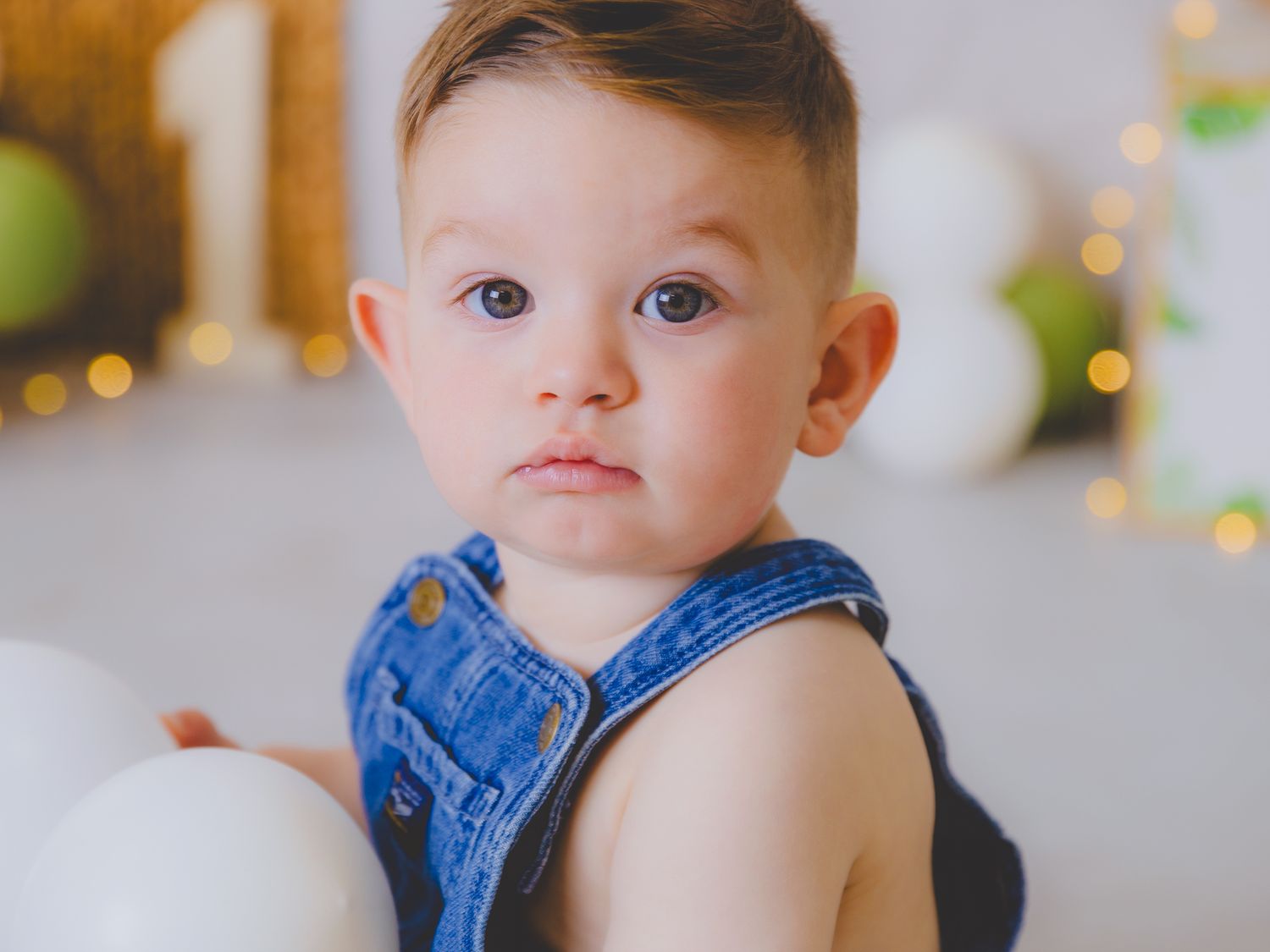 Retrato de un bebé sentado cerca de la decoración de cumpleaños con el número uno.