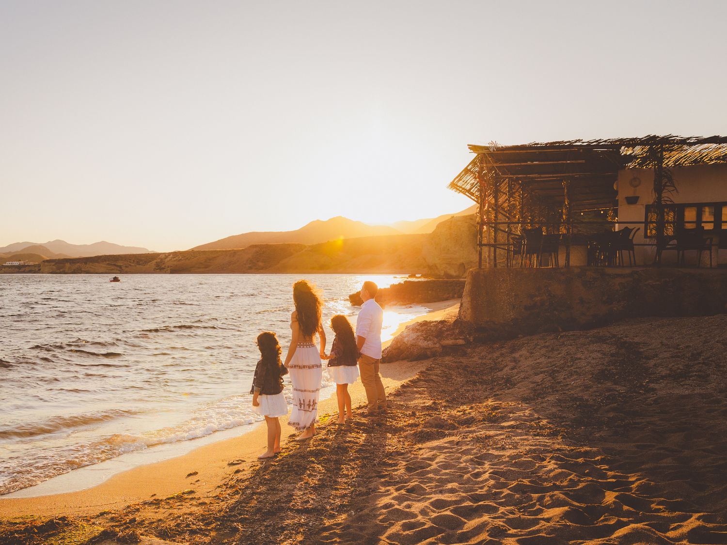 Fotografía de exteriores de comunión en familia a orilla de la playa en Cabo de Gata al atardecer.