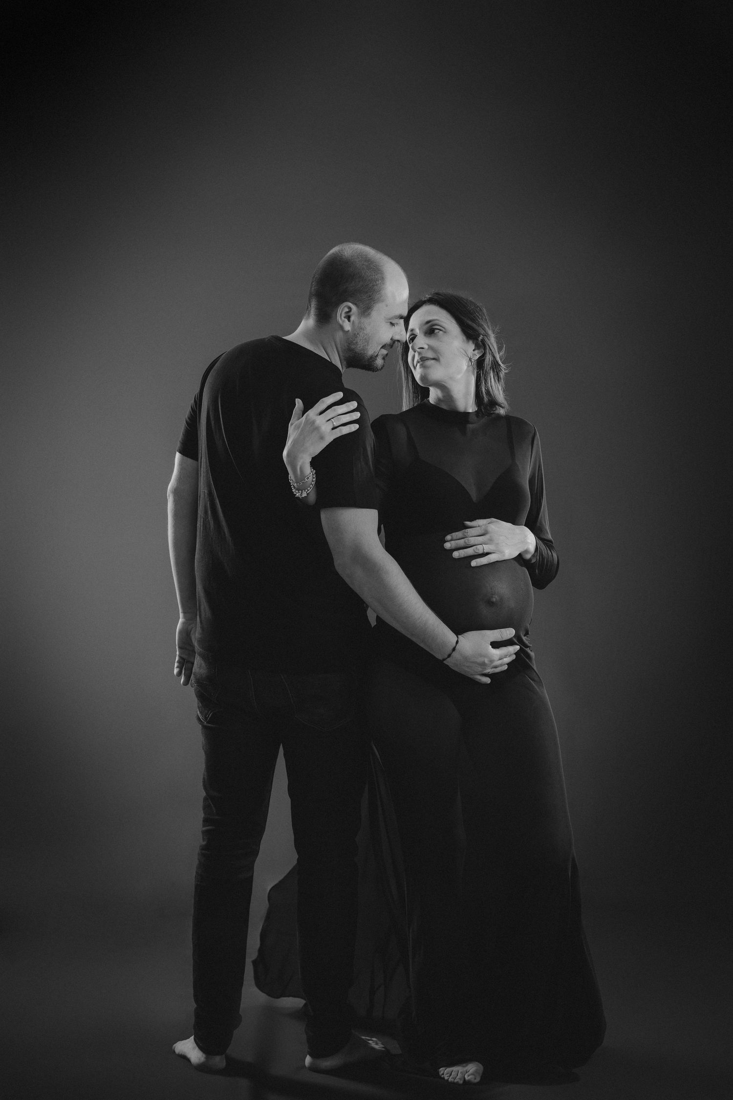 Una pareja abrazados y mirándose en una foto en blanco y negro de su reportaje de embarazo en Almería.
