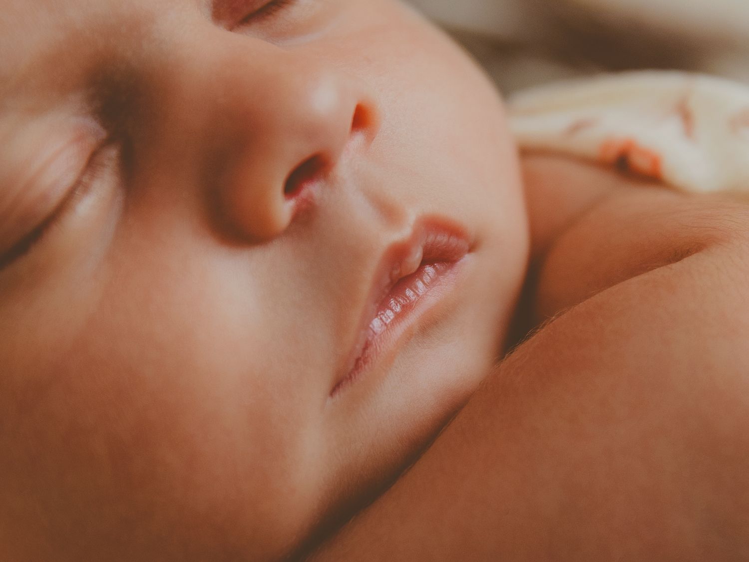 Primer plano del rostro de un bebé recién nacido dormido, con rasgos delicados y piel suave.