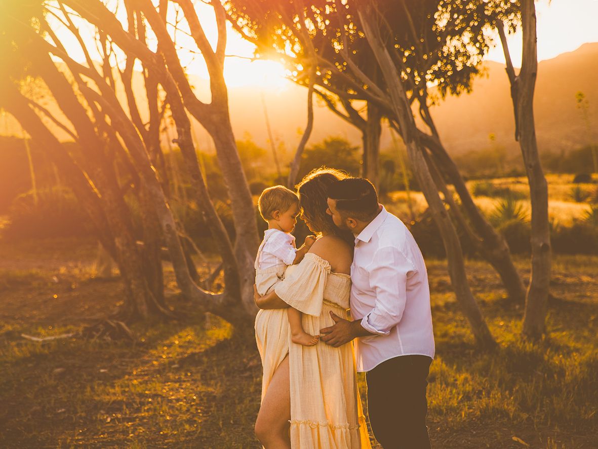 Fotografía de una familia y su hijo que se abrazan en un rincón precioso de Cabo de Gata al atardecer en su sesión de embarazo.