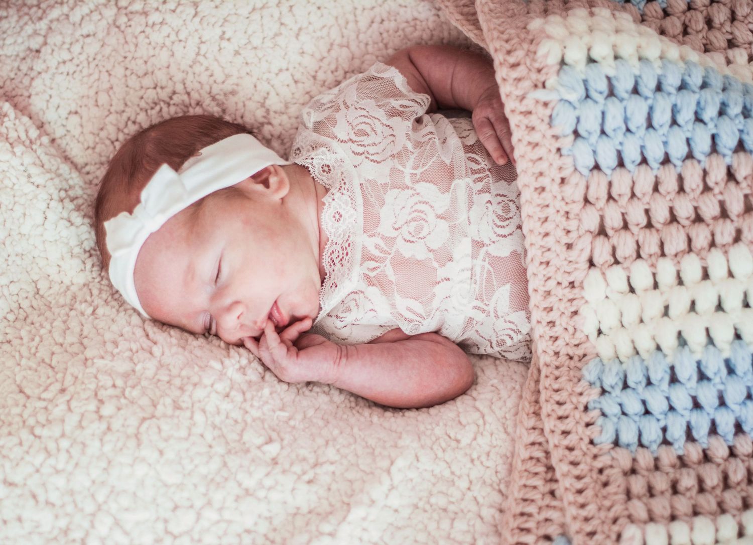 Newborn sleeping peacefully on pink and blue patterned blanket in sequential photos.