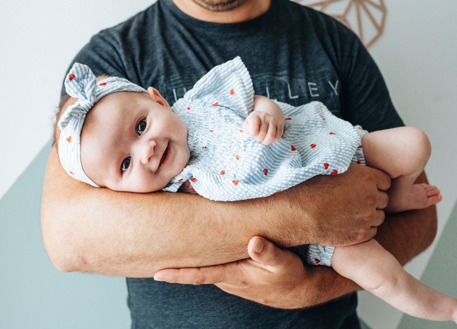 A sequence showing a baby being cradled in someone's arms wearing a floral outfit.