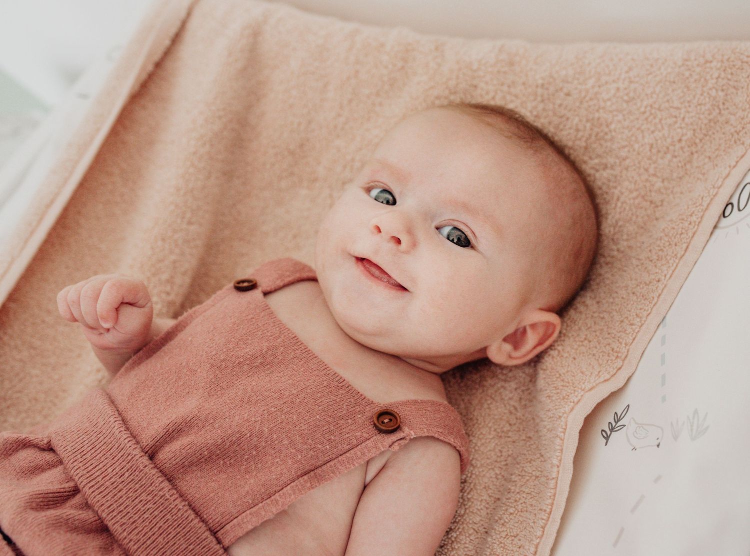 A collection of minimalist portraits showing a baby on pink textured fabric.