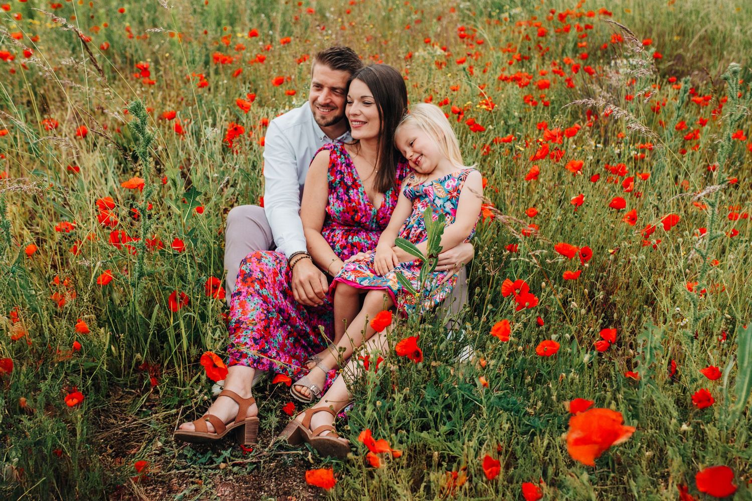 Couple shares tender moments in a blooming poppy field during sunset.