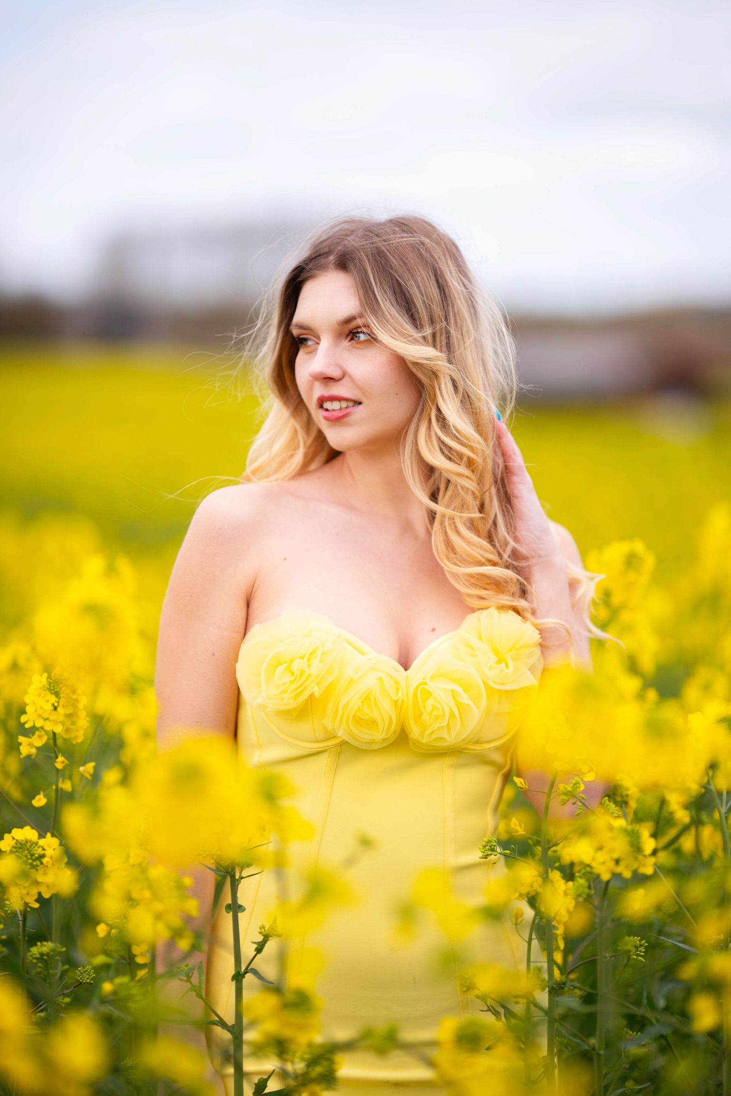 Spring fashion photography in a vibrant yellow flower field with matching dress.