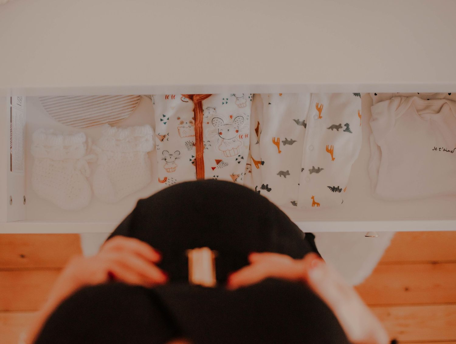 Top-down view of pregnant belly with hands gently resting on it.