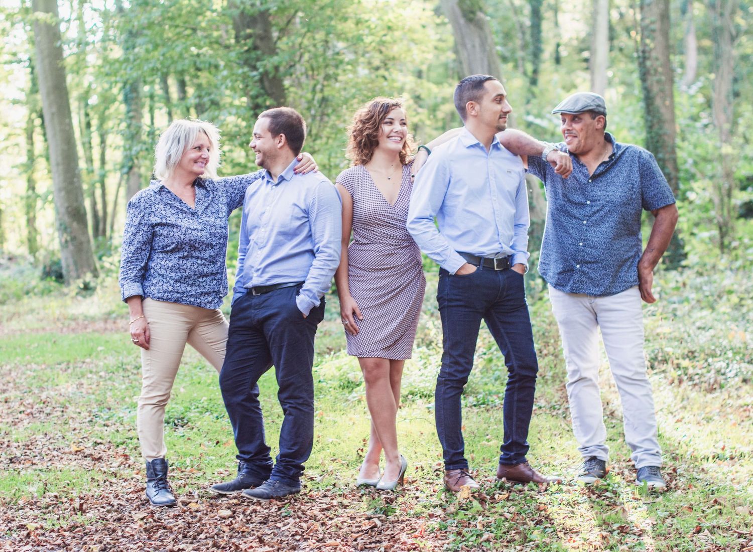 Group lounging together on fallen leaves in a wooded area during autumn.