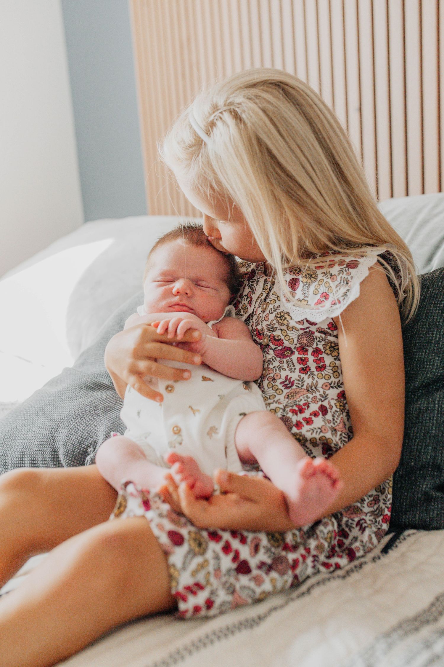 A baby resting on floral patterned bedding in soft natural light.