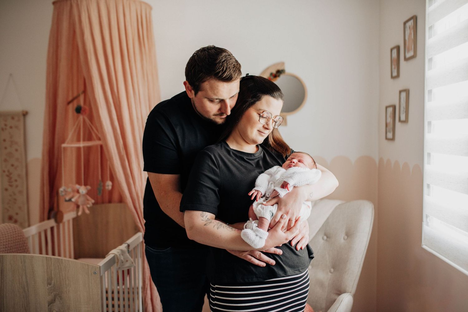 A couple shares an intimate moment in a nursery decorated with pink curtains.