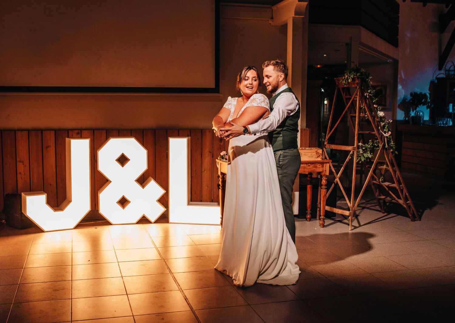 Illuminated dance floor setup with lighting equipment and decorations at a wedding reception.