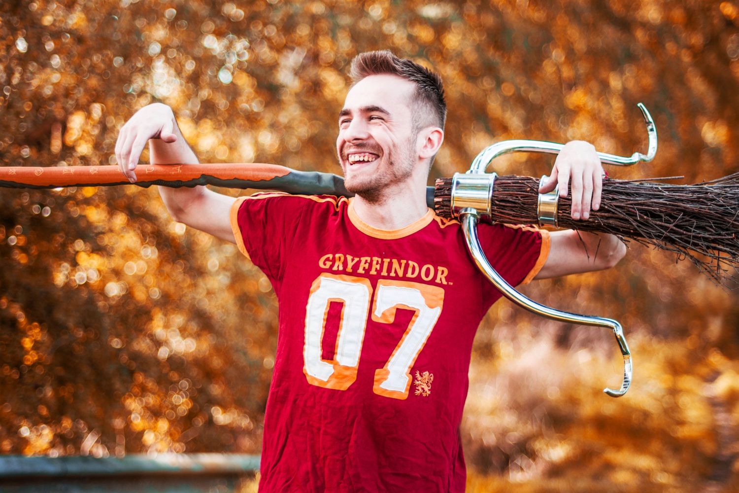 Person wearing red sports jersey poses with autumn foliage in background.