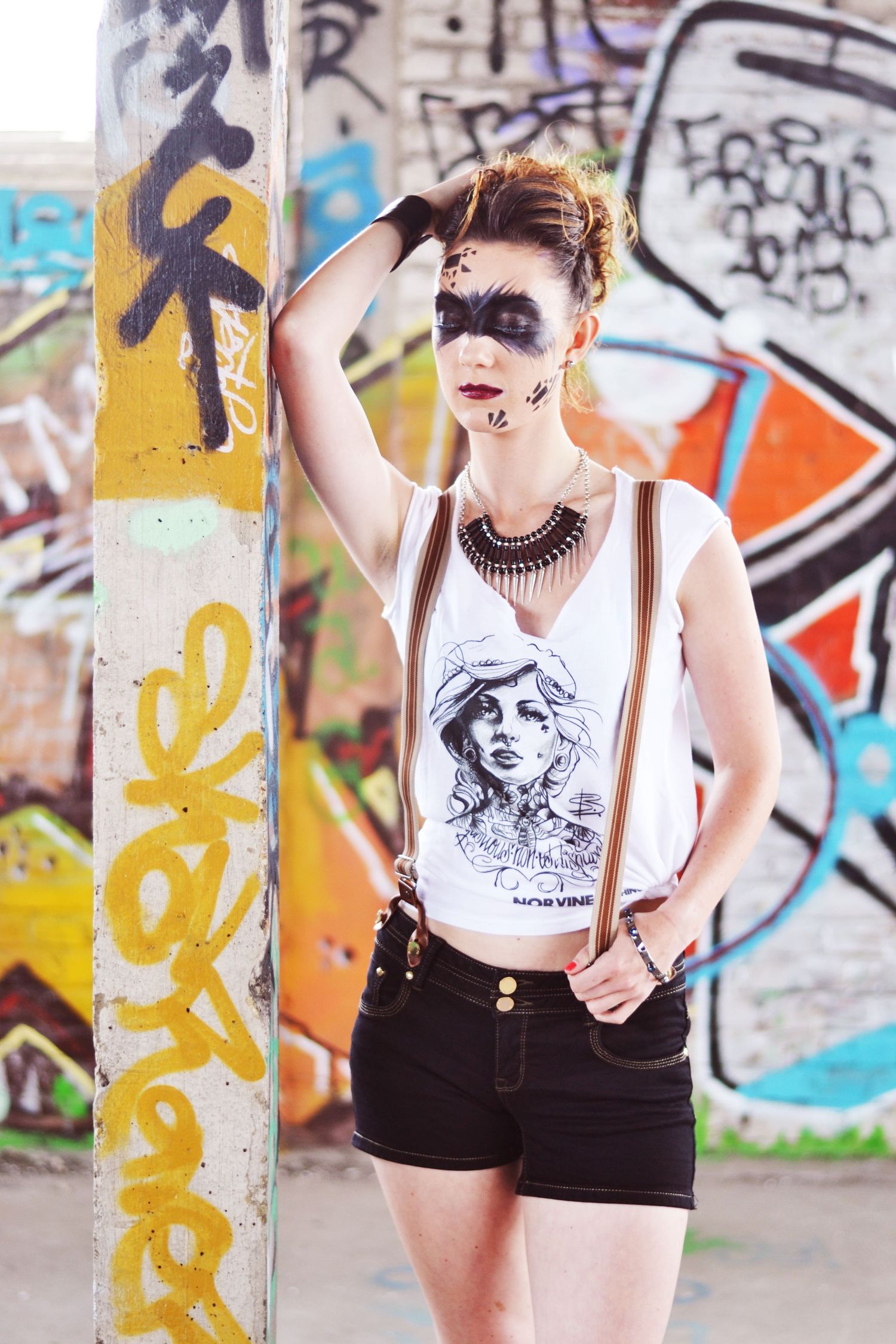 Street style fashion shoot with graphic tank top and shorts against colorful graffiti.