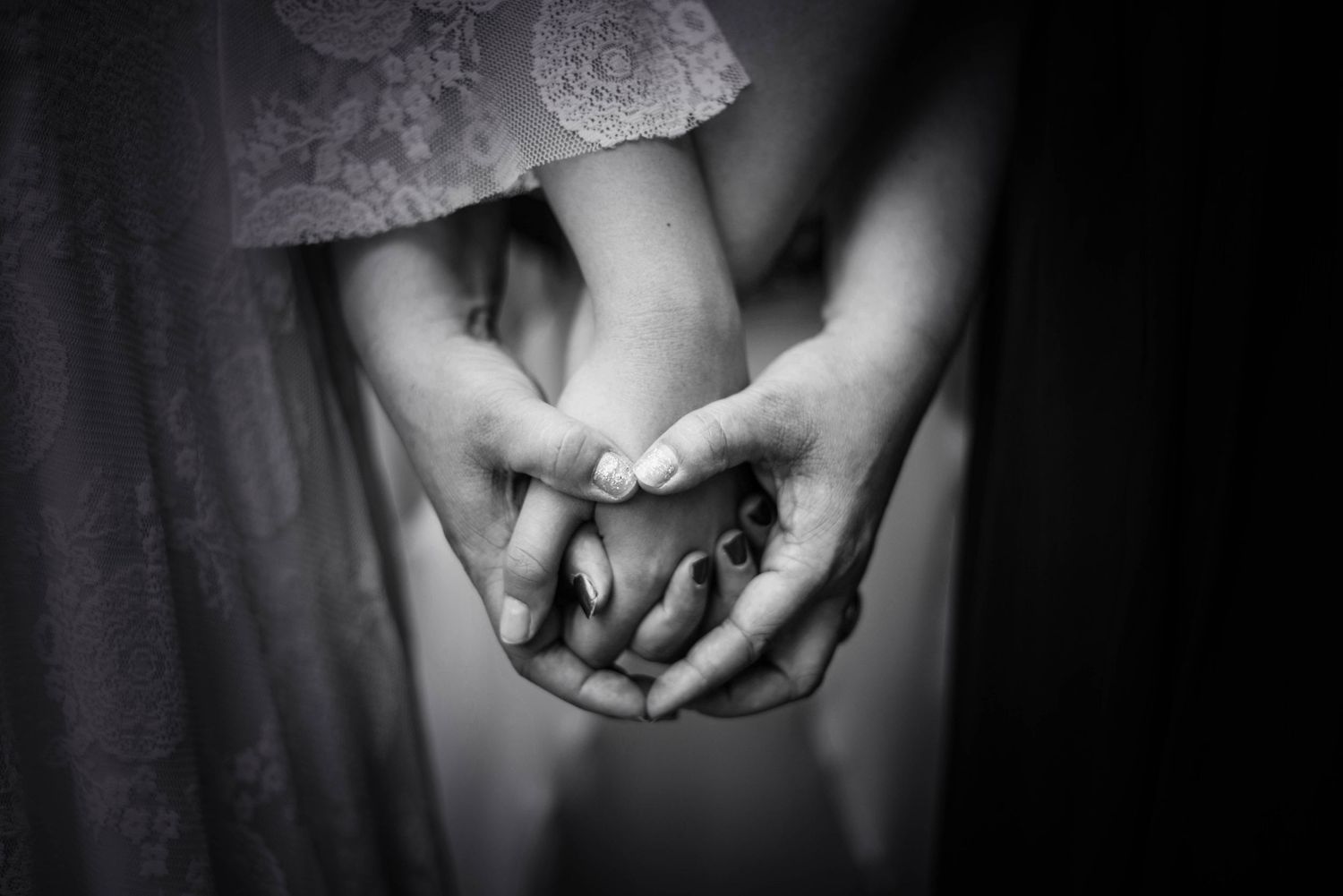 Artistic black and white close-up of hands against dark background.