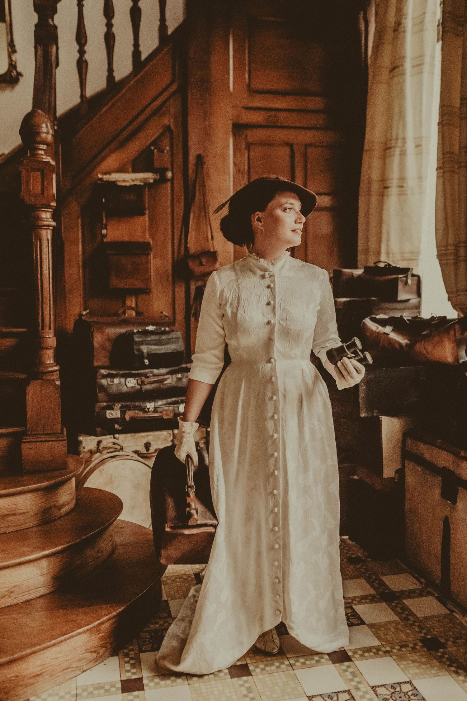 Historical scene featuring Victorian-era white dress near wooden staircase.