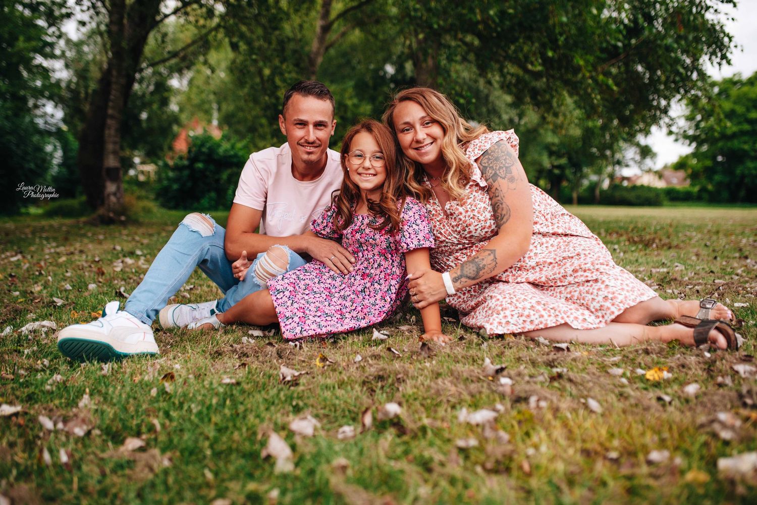 Family lying together on grass during outdoor photo session in park setting.