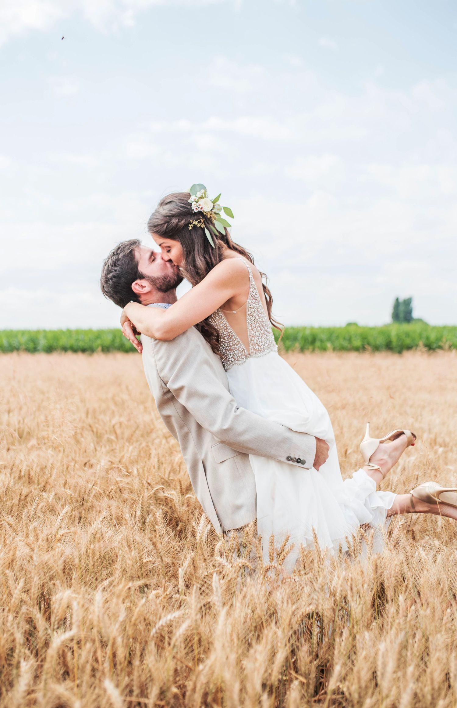 Newlyweds share an intimate dance in a sunlit wheat field during their countryside wedding.