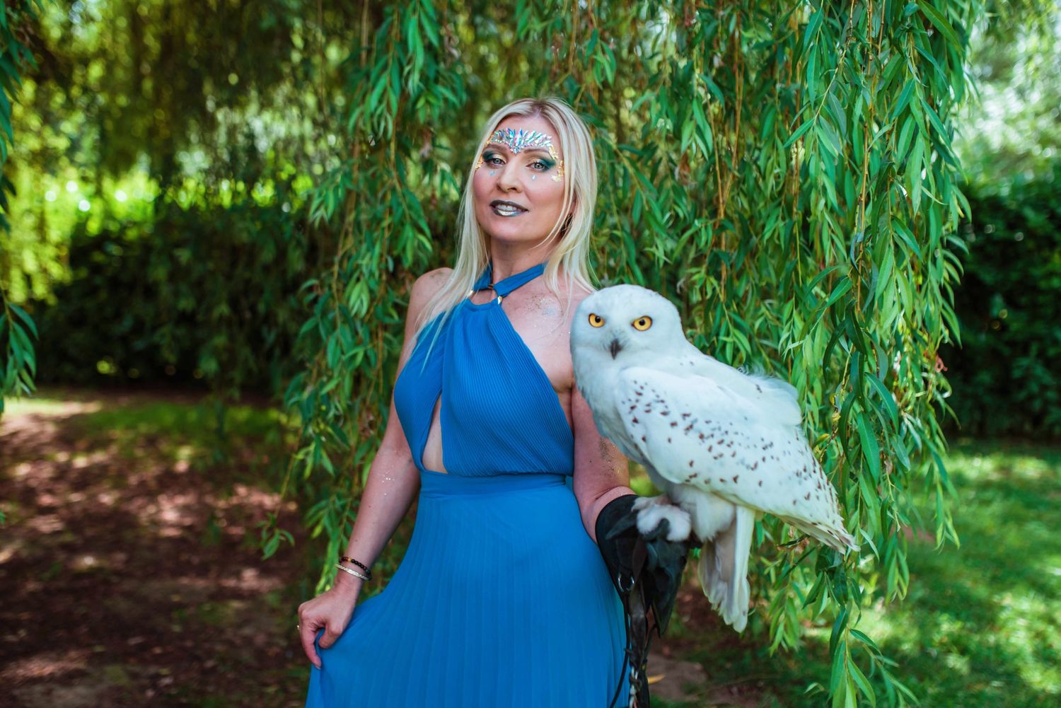 Series of outdoor portraits with person in blue dress holding white owl among green foliage.