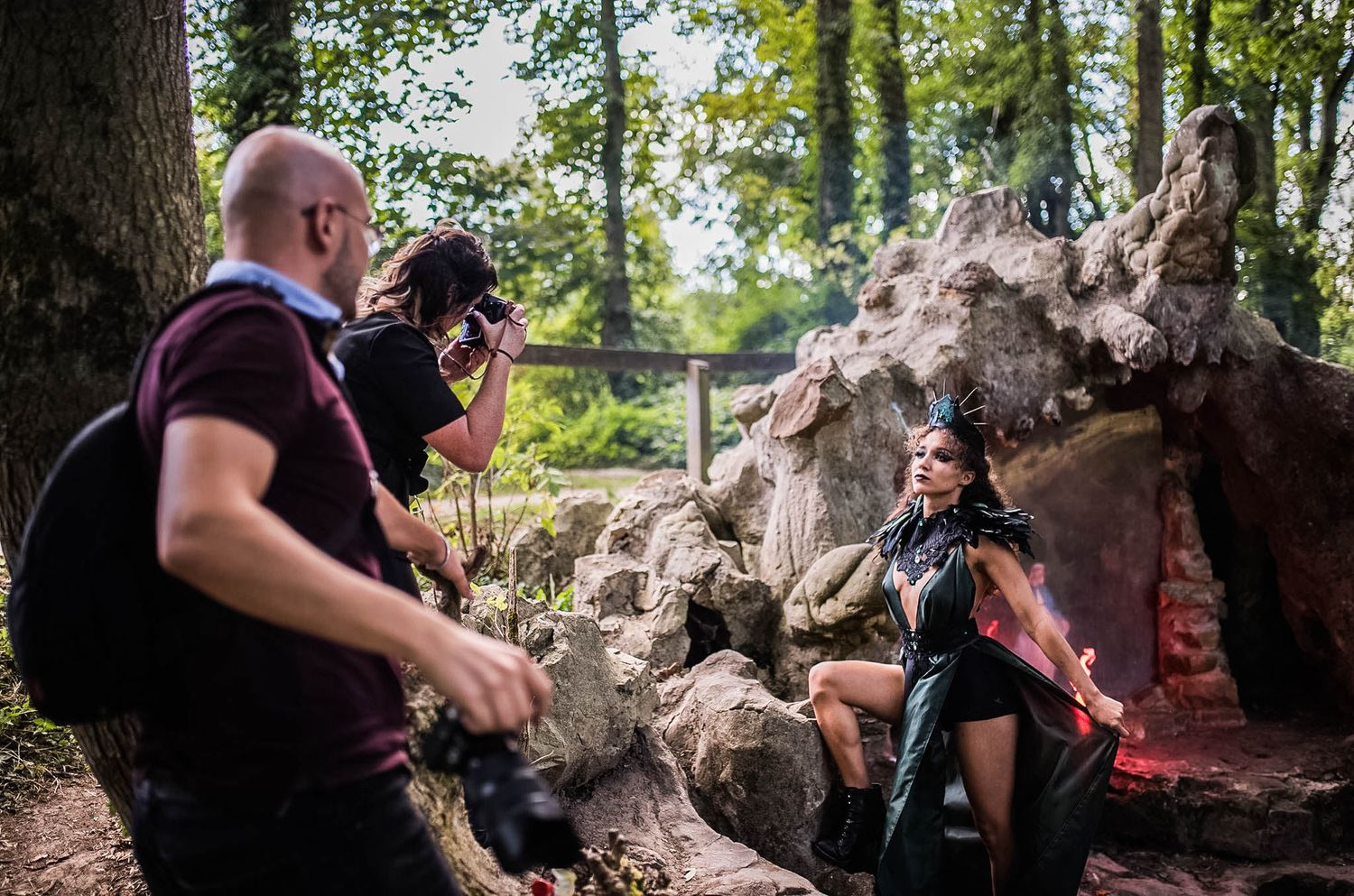 Professional photographer working with camera equipment in a wooded outdoor setting.