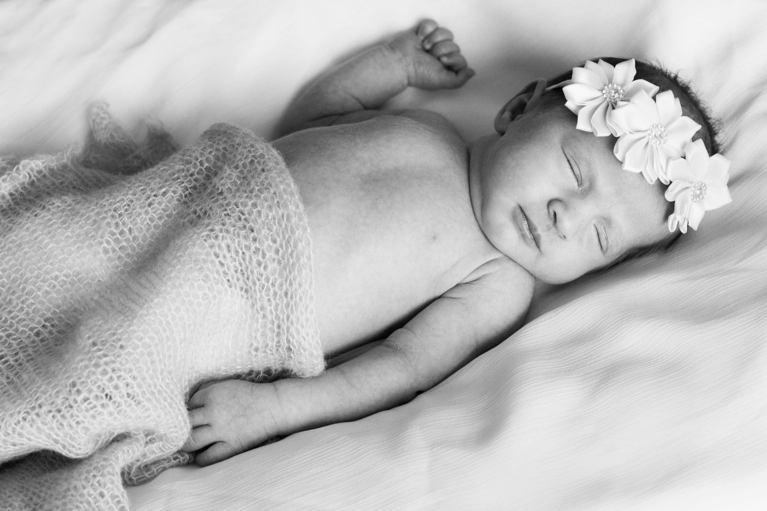 Black and white close-up of infant sleeping peacefully on soft blanket.