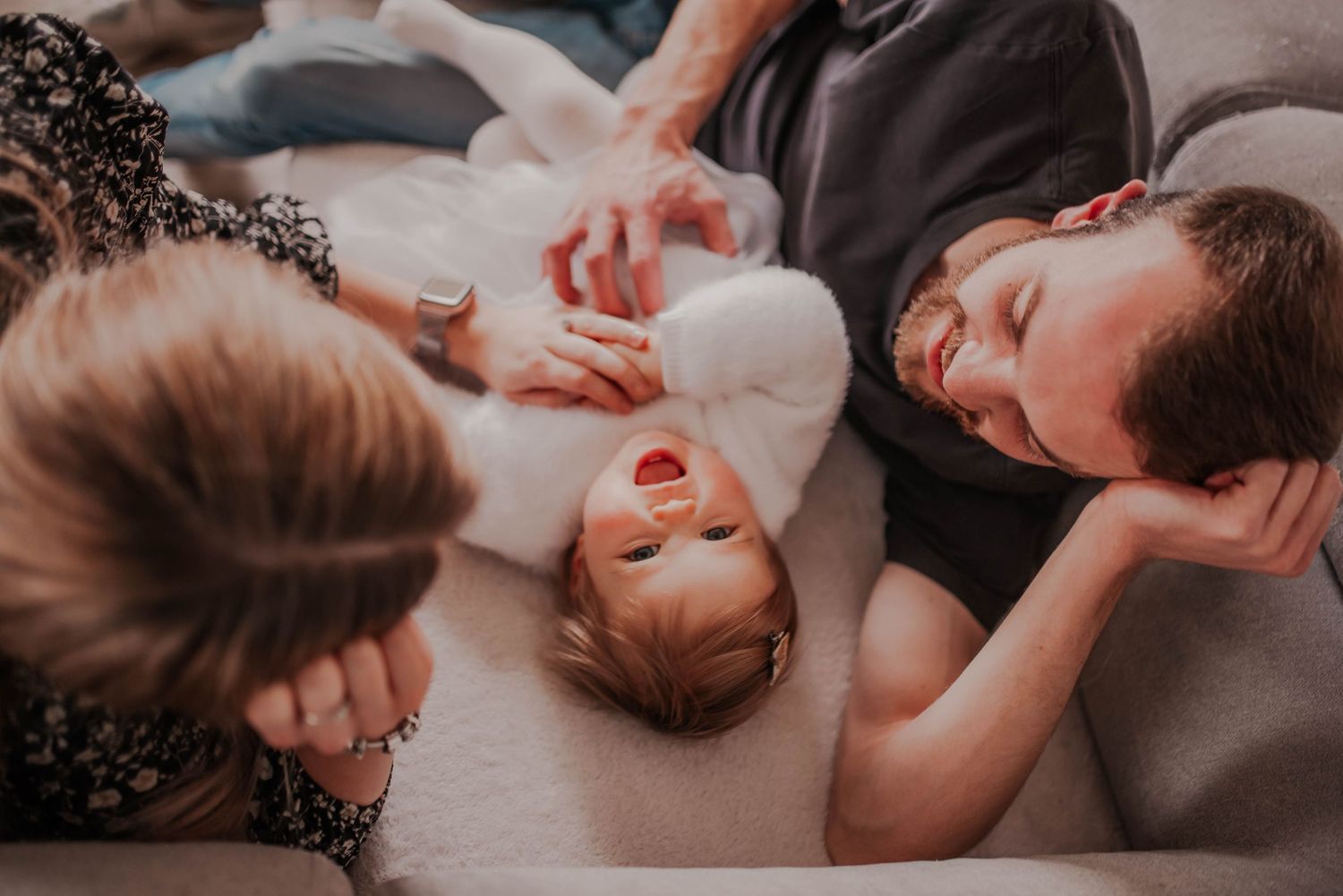 A tender family moment as they lay together with their newborn baby on a cozy surface.