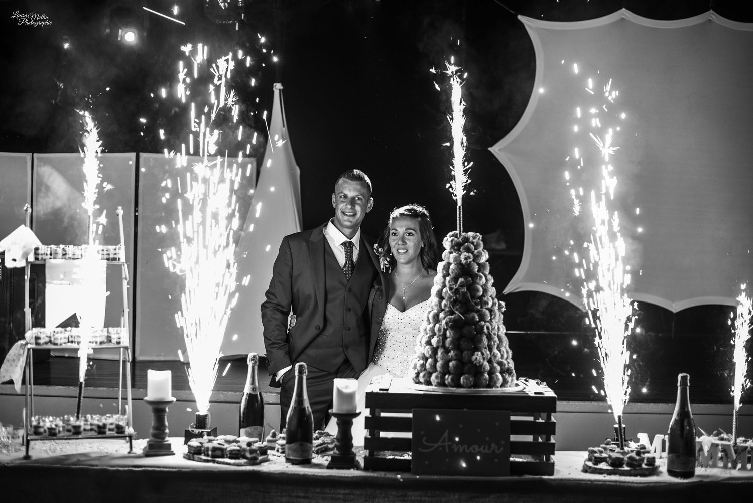 Wedding reception with sparklers creating dramatic light effects in black and white.