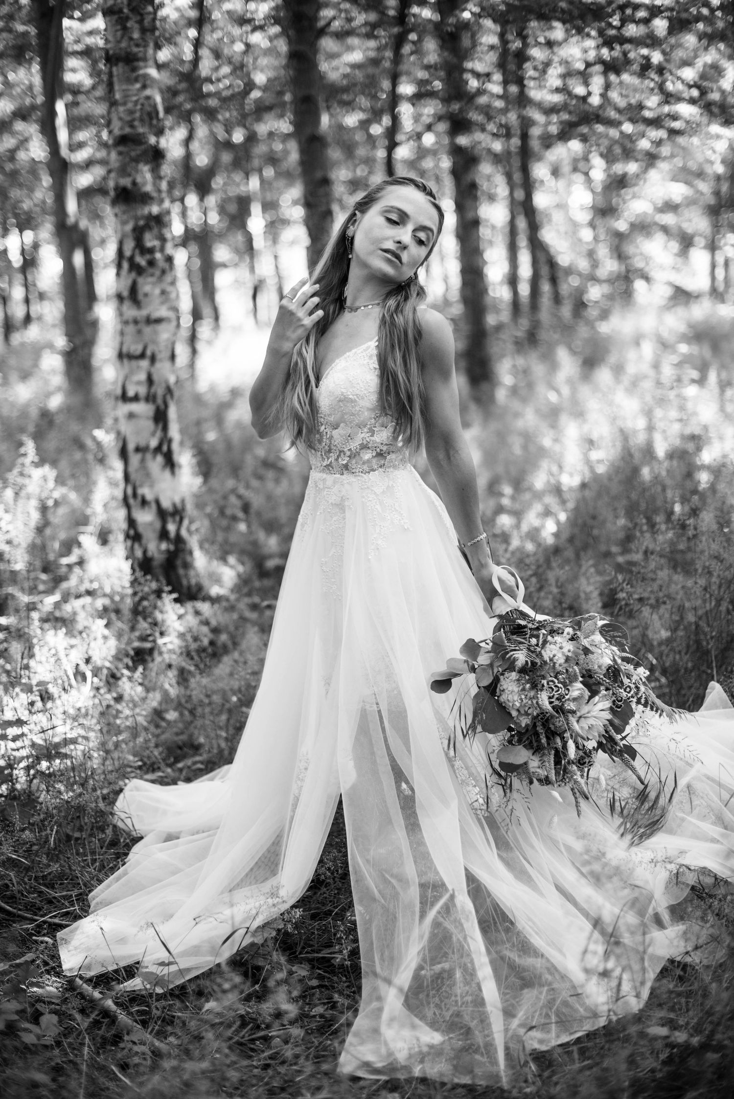 Ethereal black and white photos of a person in a flowing white dress dancing in a forest setting.