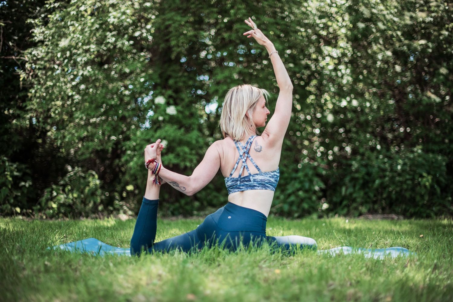 Yoga session in nature with blue exercise mat among green foliage.