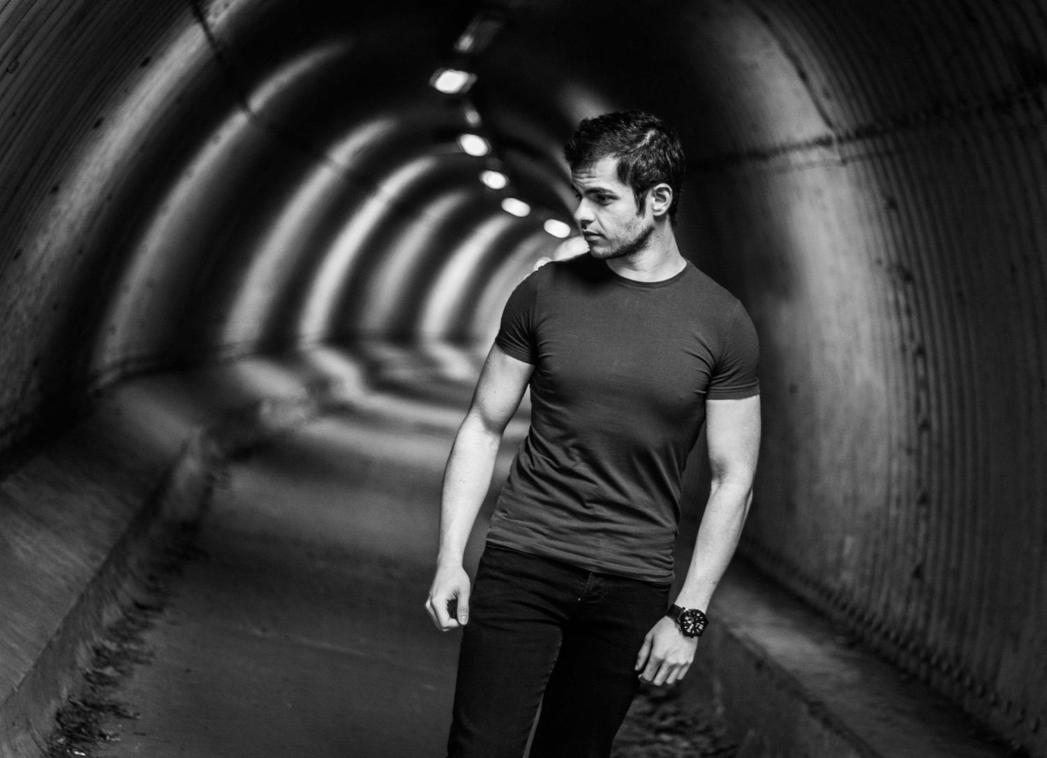 Dramatic black and white portrait in tunnel with leading lines and moody lighting.