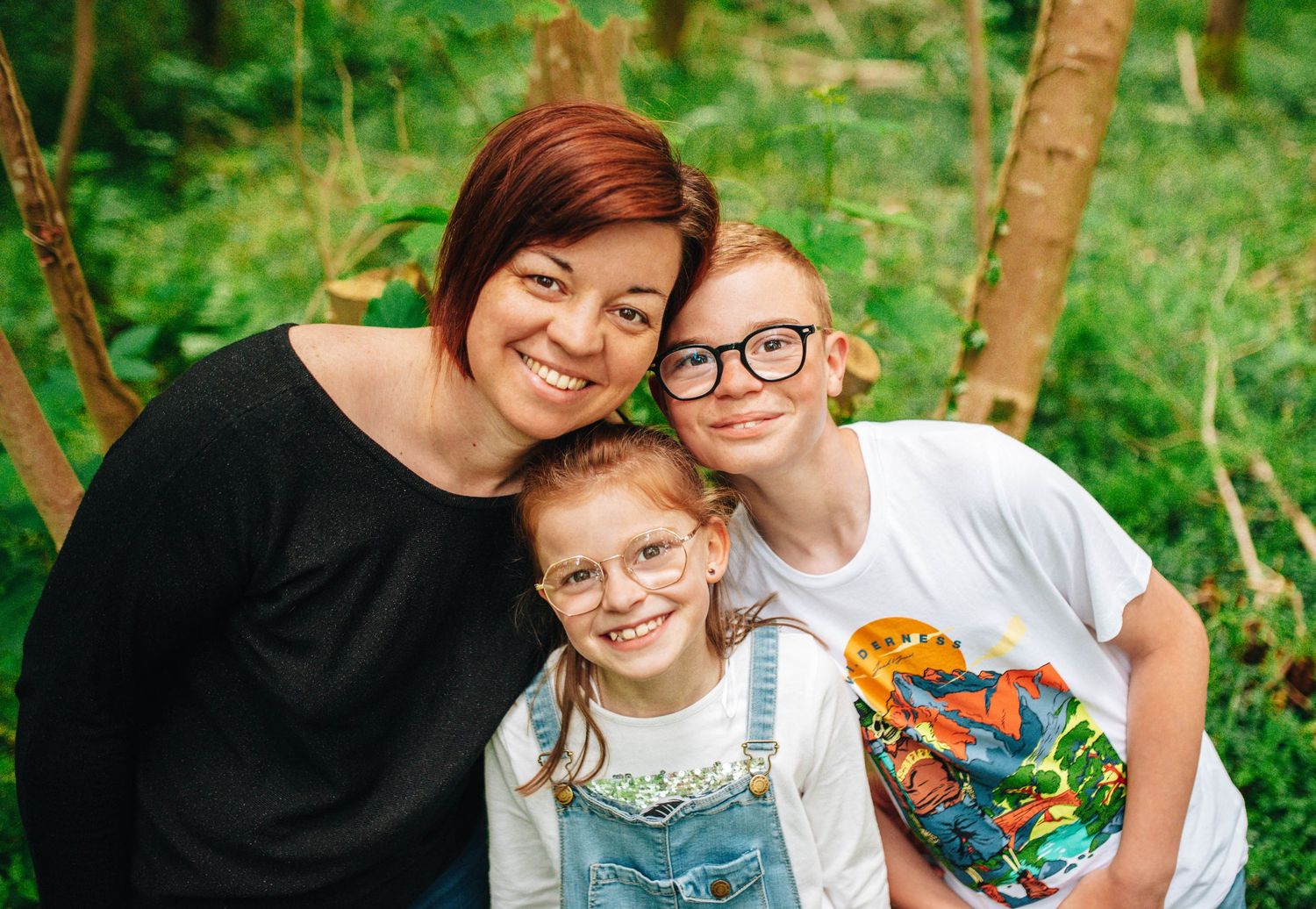 A family photo series taken in a lush green forest setting.