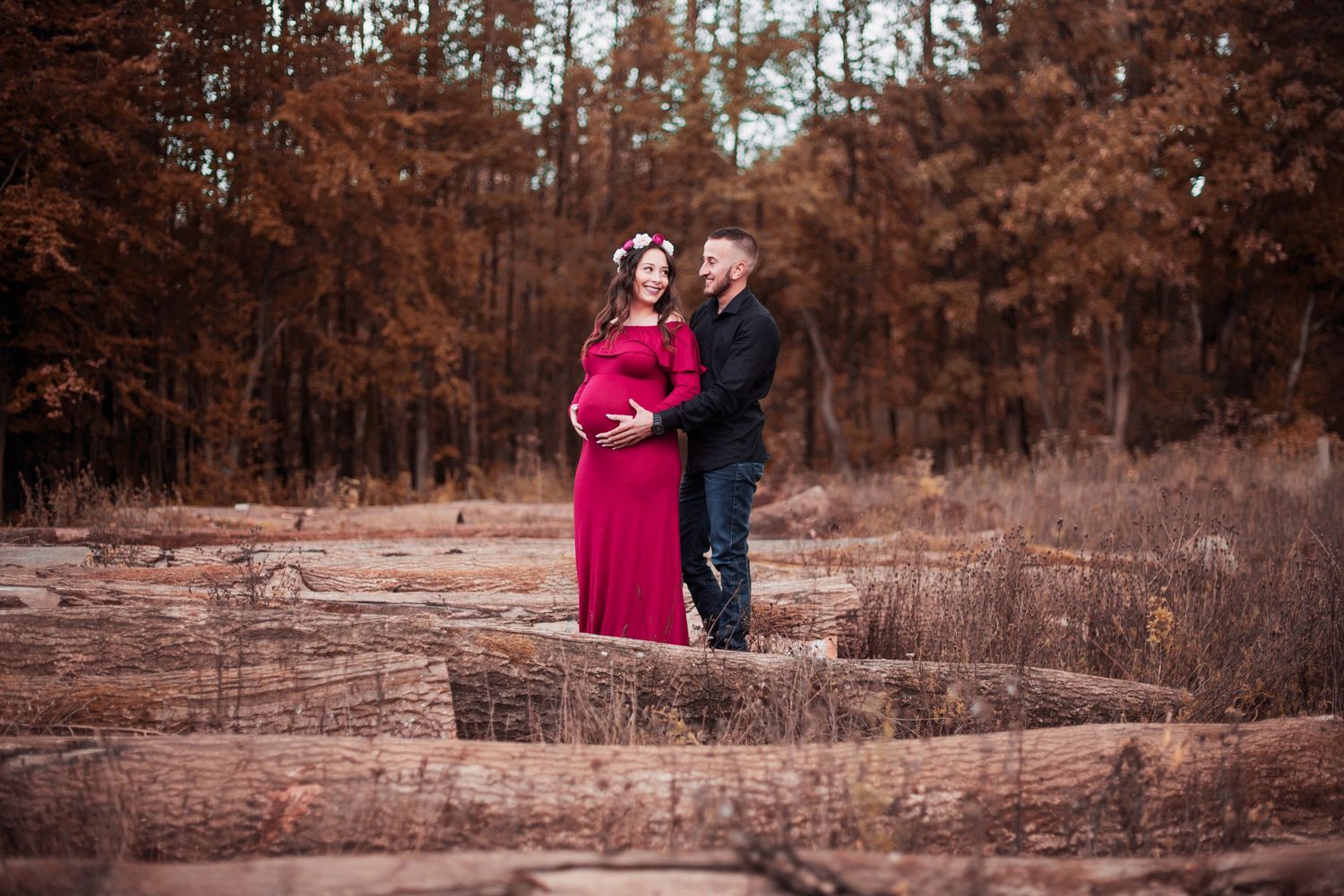 Romantic maternity photos at sunset with rustic wooden fence background.