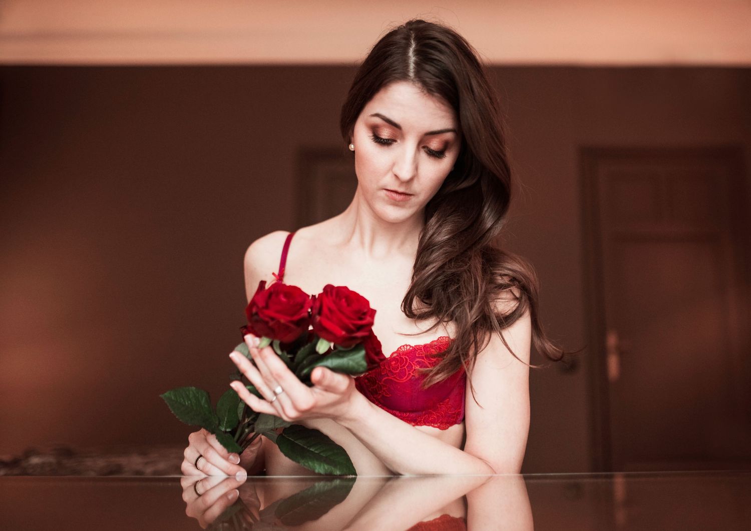 Elegant boudoir photography featuring red roses in warm, moody lighting.