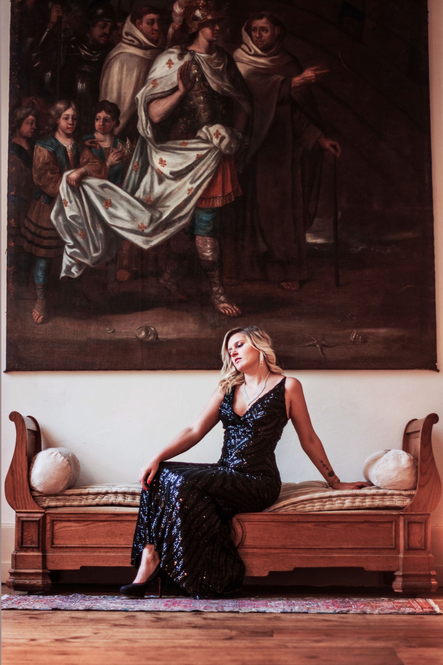 Fashion photography in an elegant historic room with classical paintings and antique furniture.