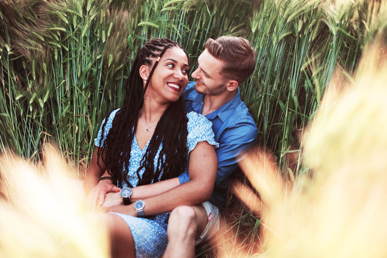 Romantic couple sharing tender moments among tall reeds in natural setting.