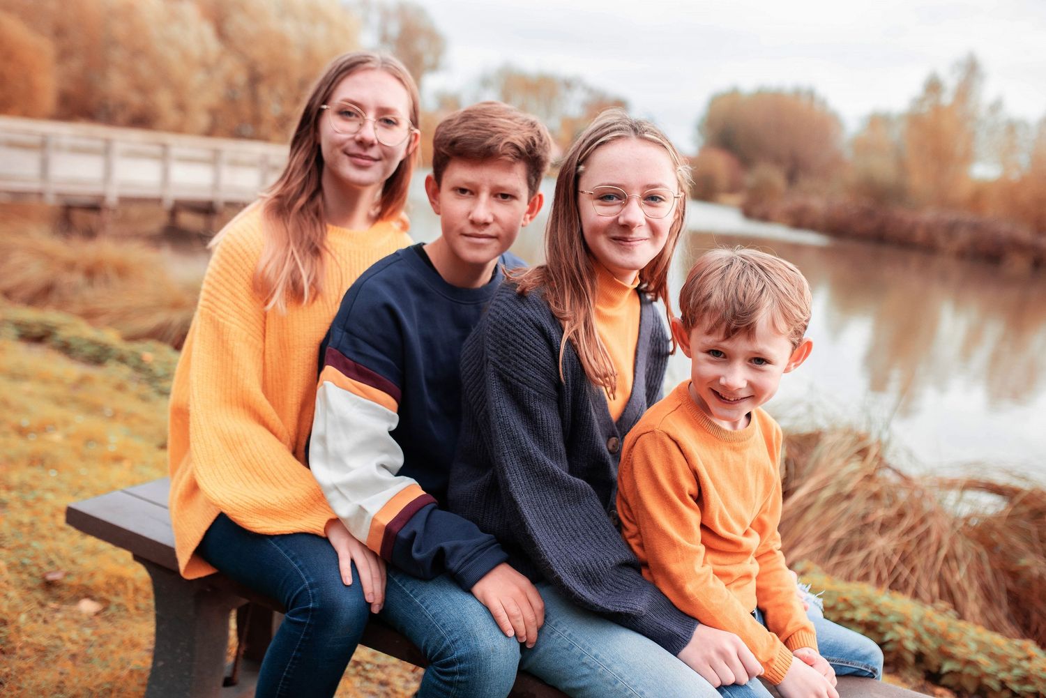 Family photo session by a pond during golden hour in autumn.