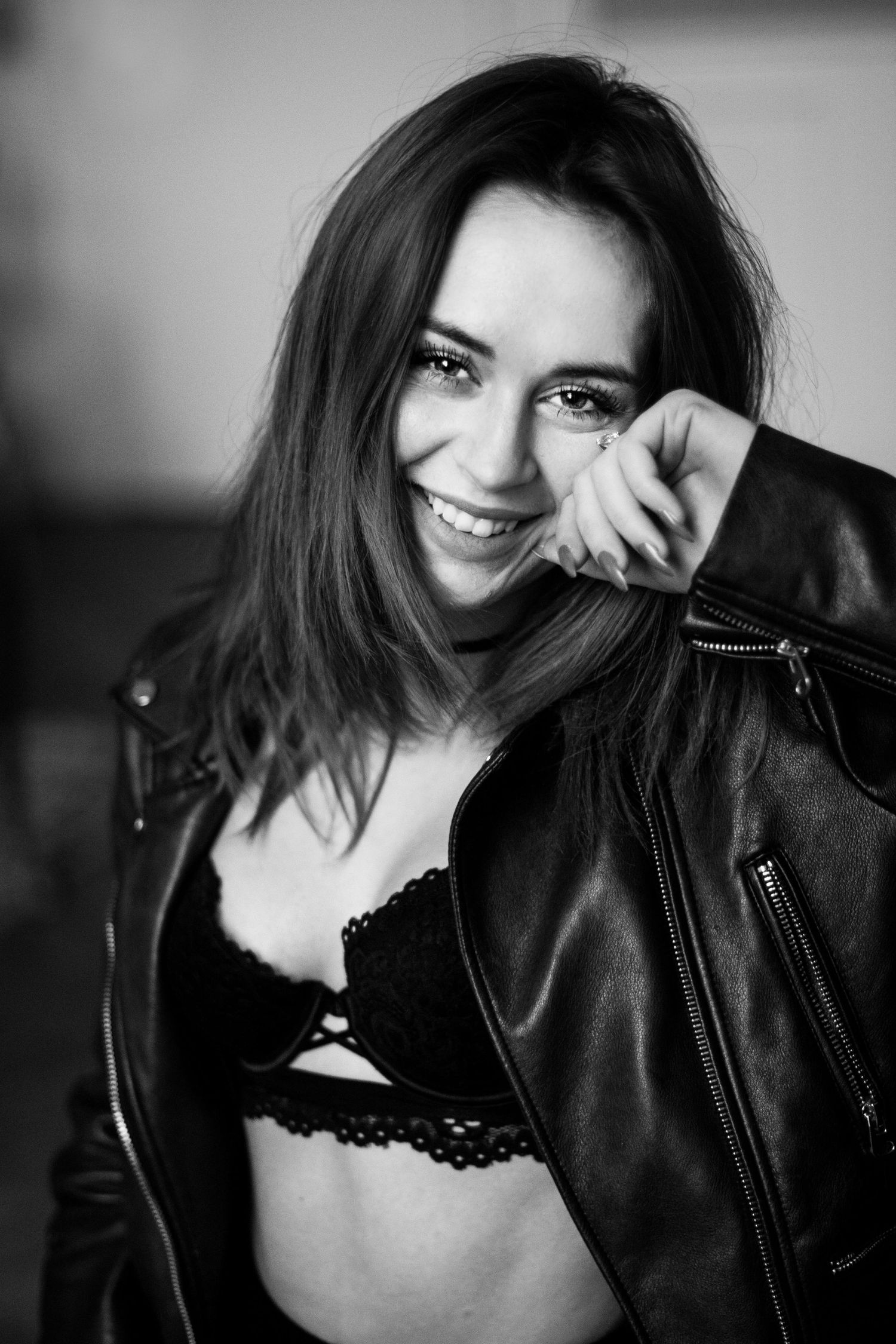 A black and white photo series showing a person in a leather jacket and black lingerie posing playfully against a dark background.