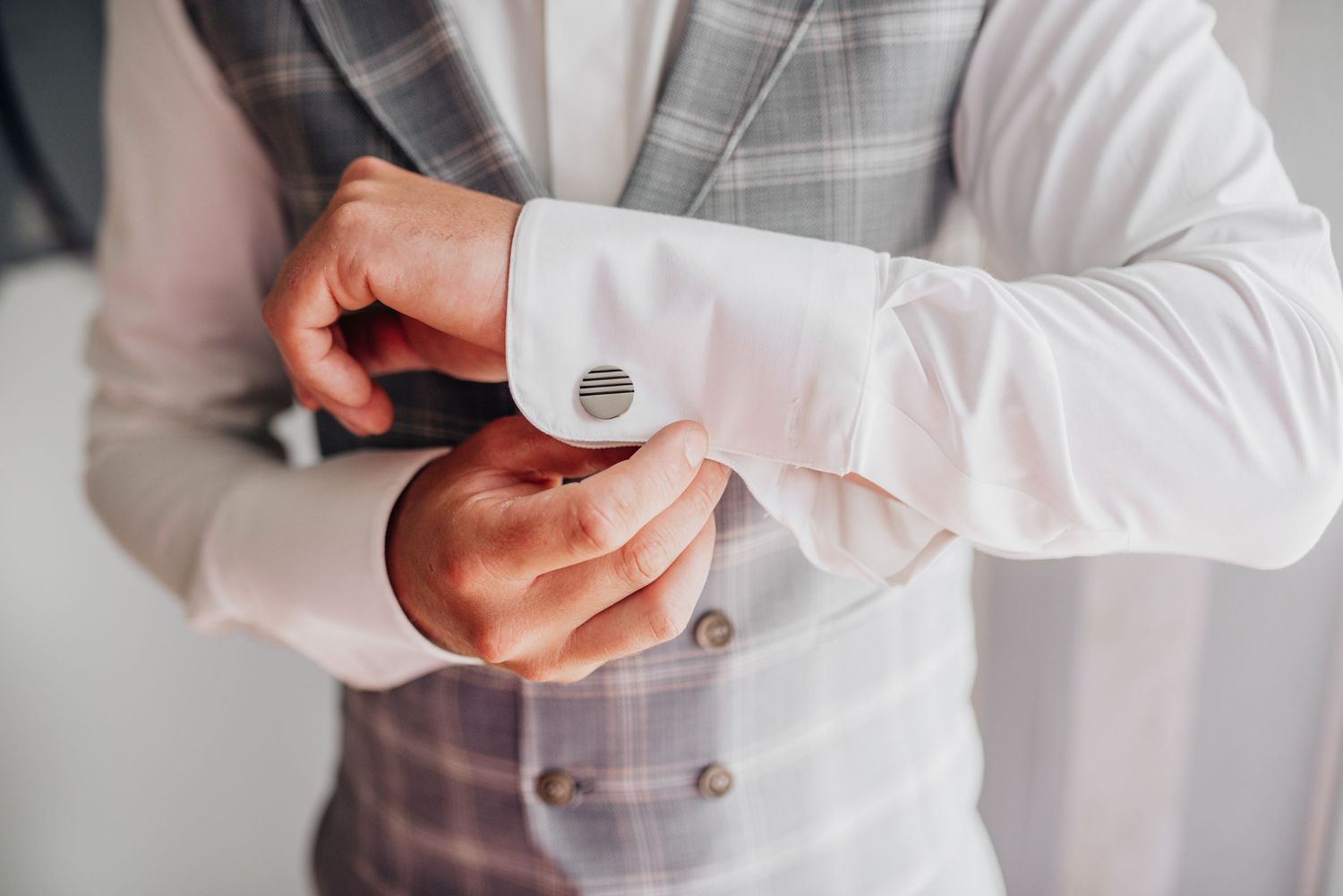 Close-up details of formal attire showing buttons and cufflinks on grey suit.